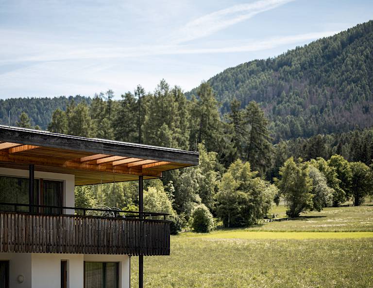 Edificio moderno ai margini di una foresta verde con una montagna sullo sfondo sotto un cielo limpido.