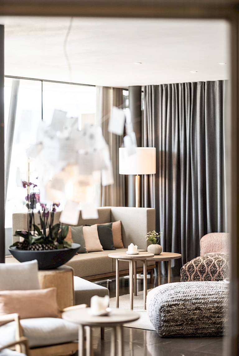 Elegante soggiorno con mobili moderni, tende grigie e cuscini decorativi in colori neutri.