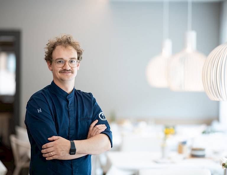 Uno chef sorride in un ristorante moderno ed elegante.