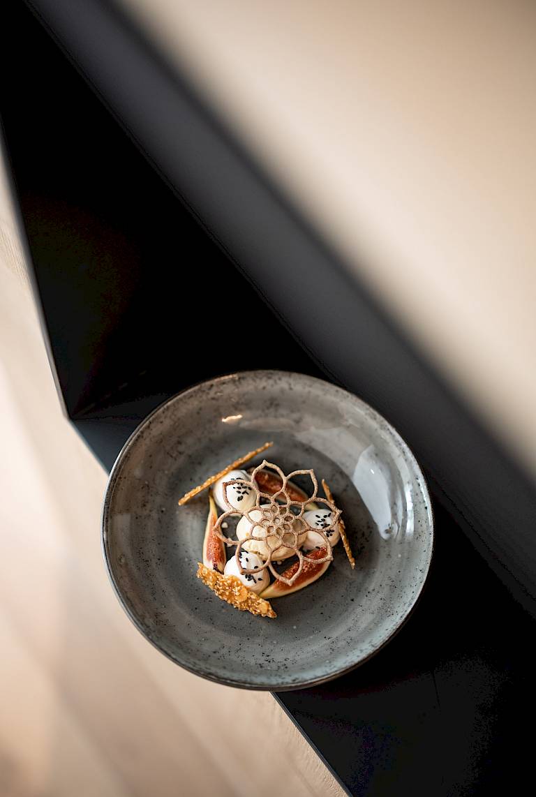 Piatto di ceramica con dessert artisticamente decorato con petali di fiori e frutti di bosco.