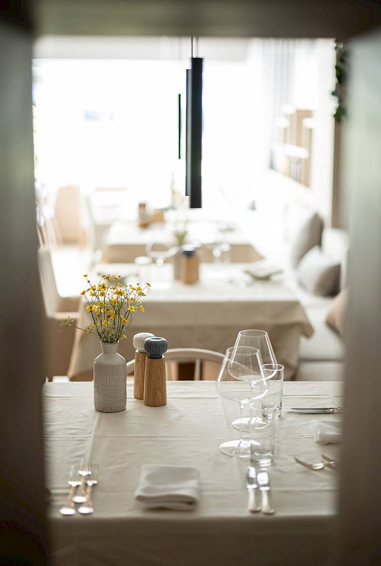 Elegante ristorante con tavolo apparecchiato, vaso di fiori e luce soffusa in atmosfera intima.