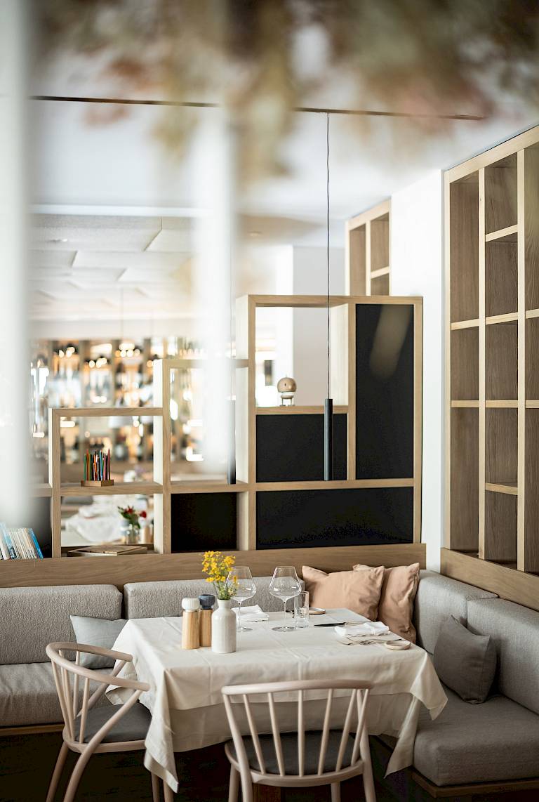 Accogliente angolo ristorante con tavola apparecchiata, due sedie in legno e illuminazione soffusa.