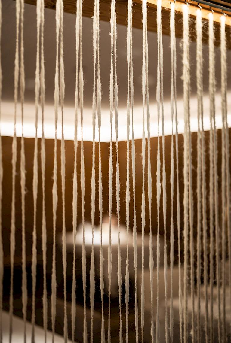 Fili appesi verticalmente creano un effetto divisorio in una stanza modernamente illuminata.