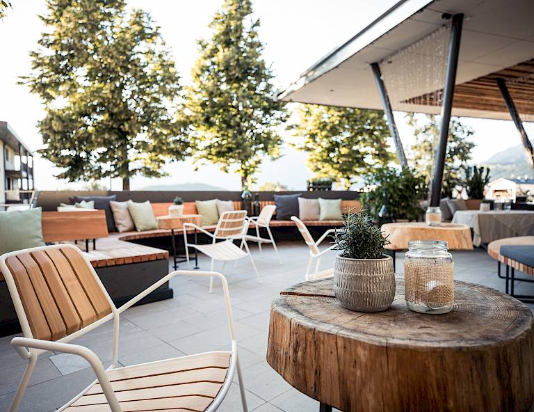 Terrazza moderna con mobili in legno e metallo, decorata con piante e luce, atmosfera tranquilla.
