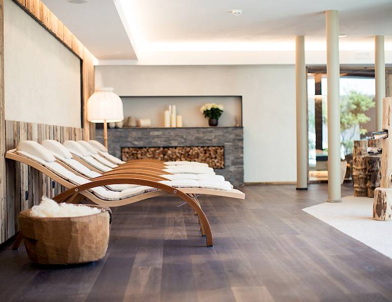Lounge benessere moderna con eleganti lettini in legno e illuminazione suggestiva. Invitante e tranquillo.