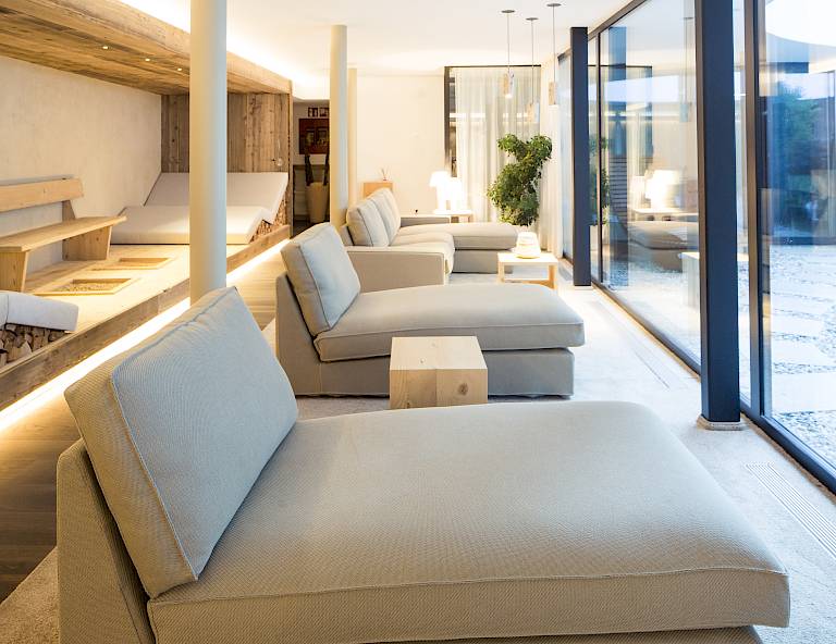 Moderna lounge benessere con lettini e vetrata che lascia entrare molta luce naturale.