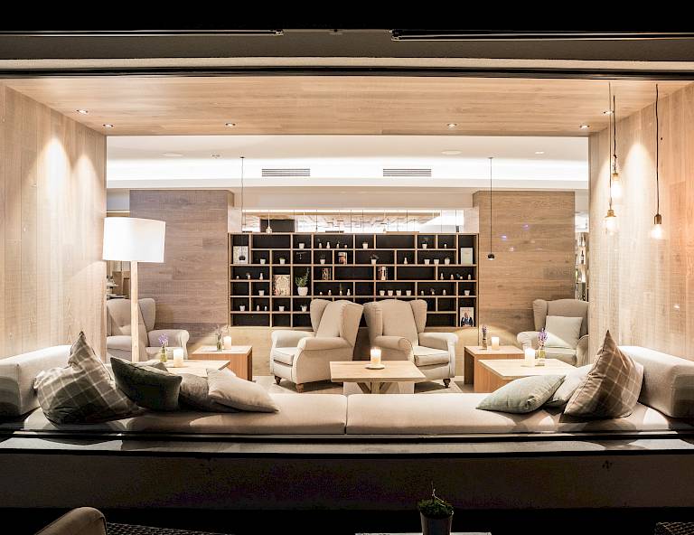 Lounge accogliente con divani e poltrone, illuminazione soffusa e scaffali pieni di libri.