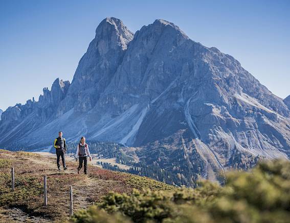 Zwei Wanderer genießen die Aussicht auf beeindruckende Berglandschaft an einem klaren, sonnigen Tag.