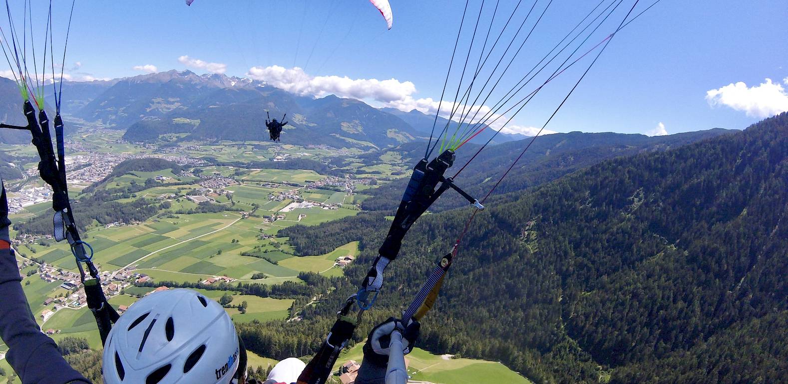 Persone che fanno parapendio su un paesaggio montano pittoresco in una giornata limpida e soleggiata.