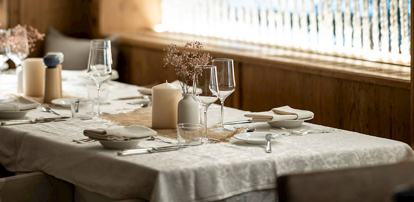 Rustic restaurant with wooden walls and set table under soft lighting. Cozy atmosphere.