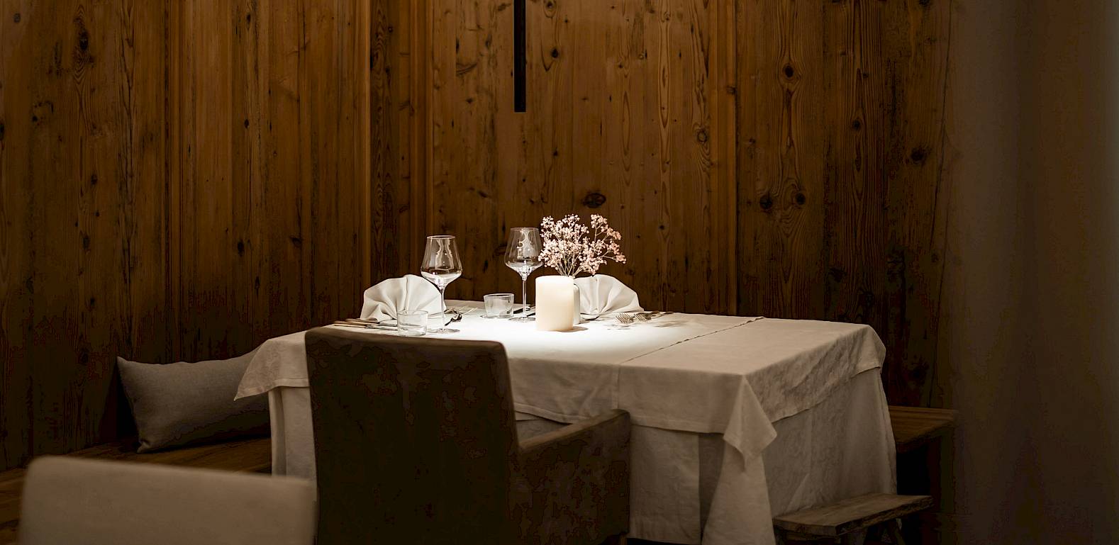 An elegant, cozy restaurant with wooden walls and a table set for two, perfectly arranged.