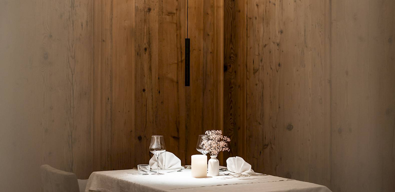 A table set with candles and napkins in a cozy, wood-paneled restaurant.