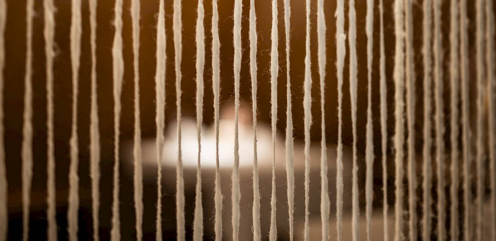 Threads hanging vertically in a modern room with a blurred background and soft lighting.