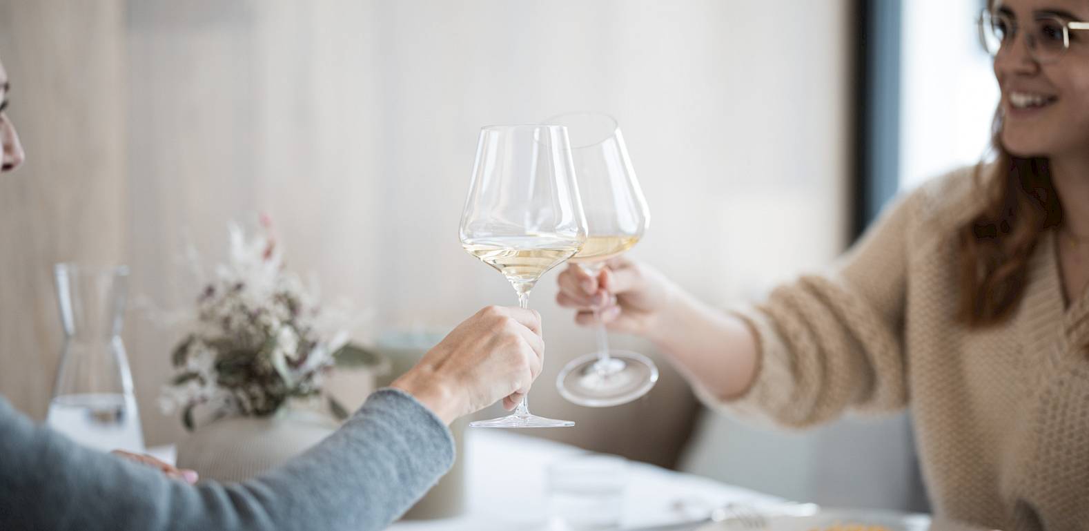 Due persone brindano con bicchieri di vino a un tavolo in un ristorante.