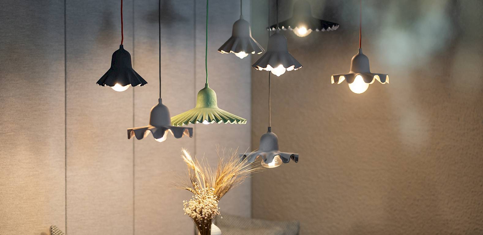 Sala da pranzo accogliente con lampade a sospensione eleganti, tavolo in legno, sedie bianche e fiori secchi.