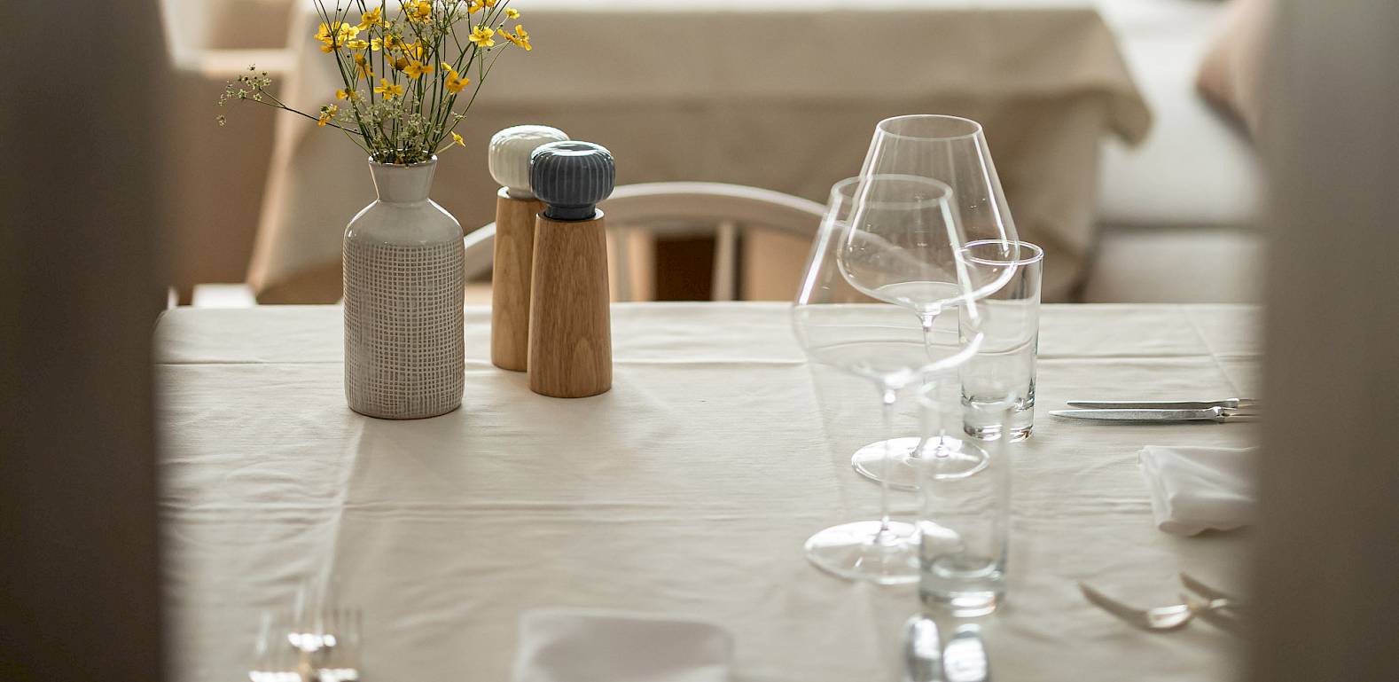Ristorante elegante con tavoli apparecchiati, vasi di fiori e illuminazione sobria, pronto per gli ospiti.