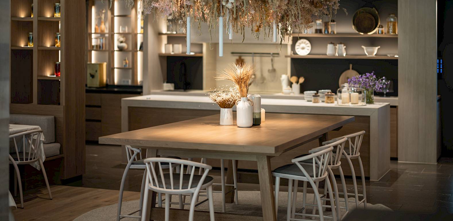 Moderner Essbereich mit Holztisch, Stühlen und einer üppigen Blumeninstallation. Zen Atmosphäre.