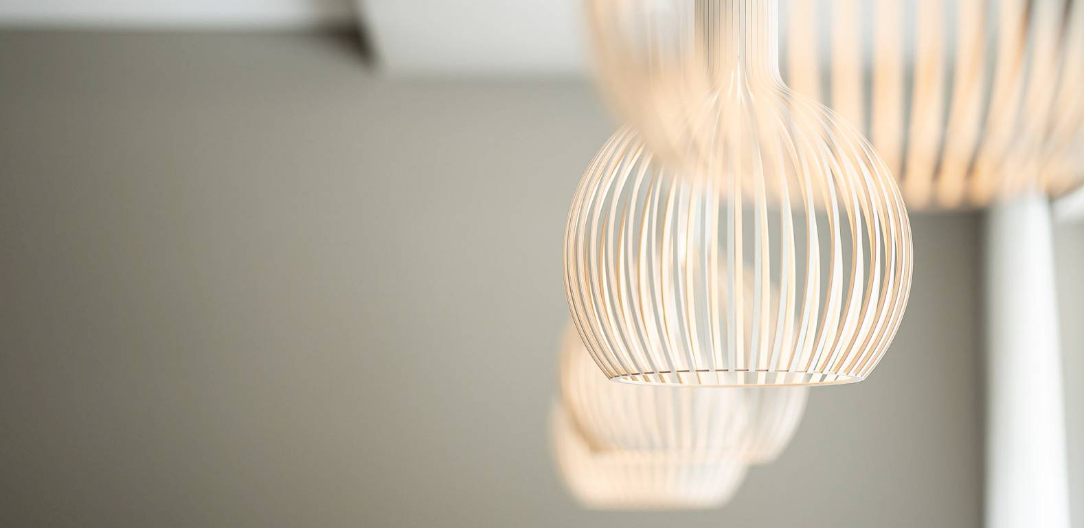 Moderne hängende Lampen in stilvollem Restaurant mit gedeckten Tischen und Blumen.