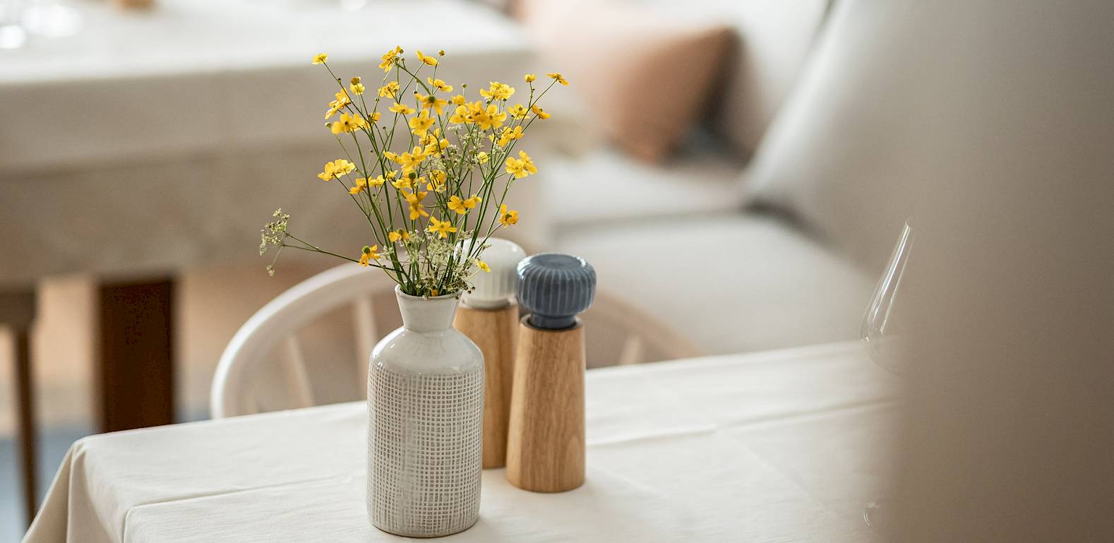 Tisch in einem gemütlichen Café mit Blumenstrauß und Salzstreuer, im Hintergrund Sofas.