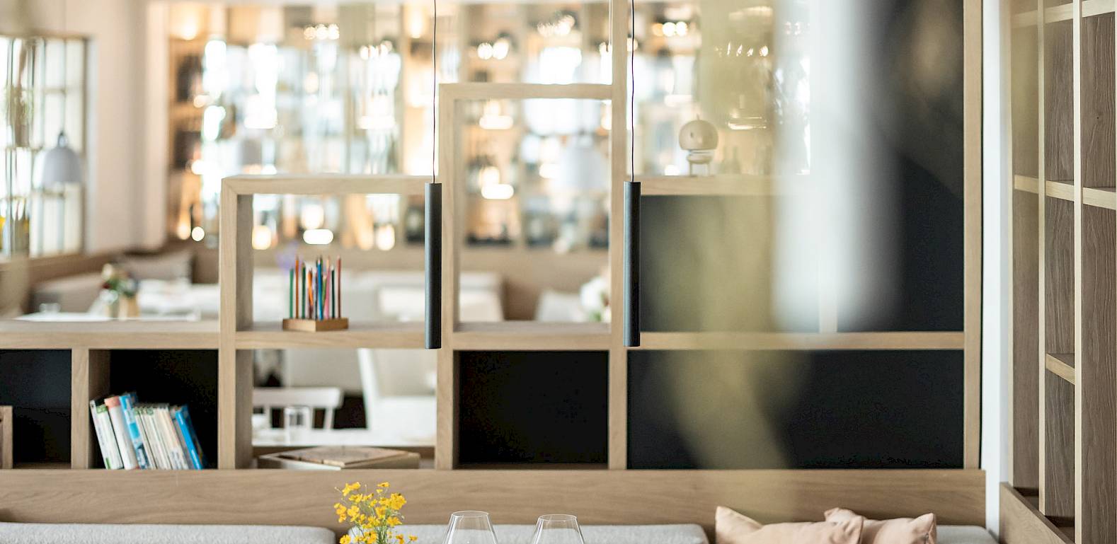 Gemütliches Restaurantinterieur mit gedecktem Tisch, grauen Sofas, Holzstühlen und weicher Beleuchtung.