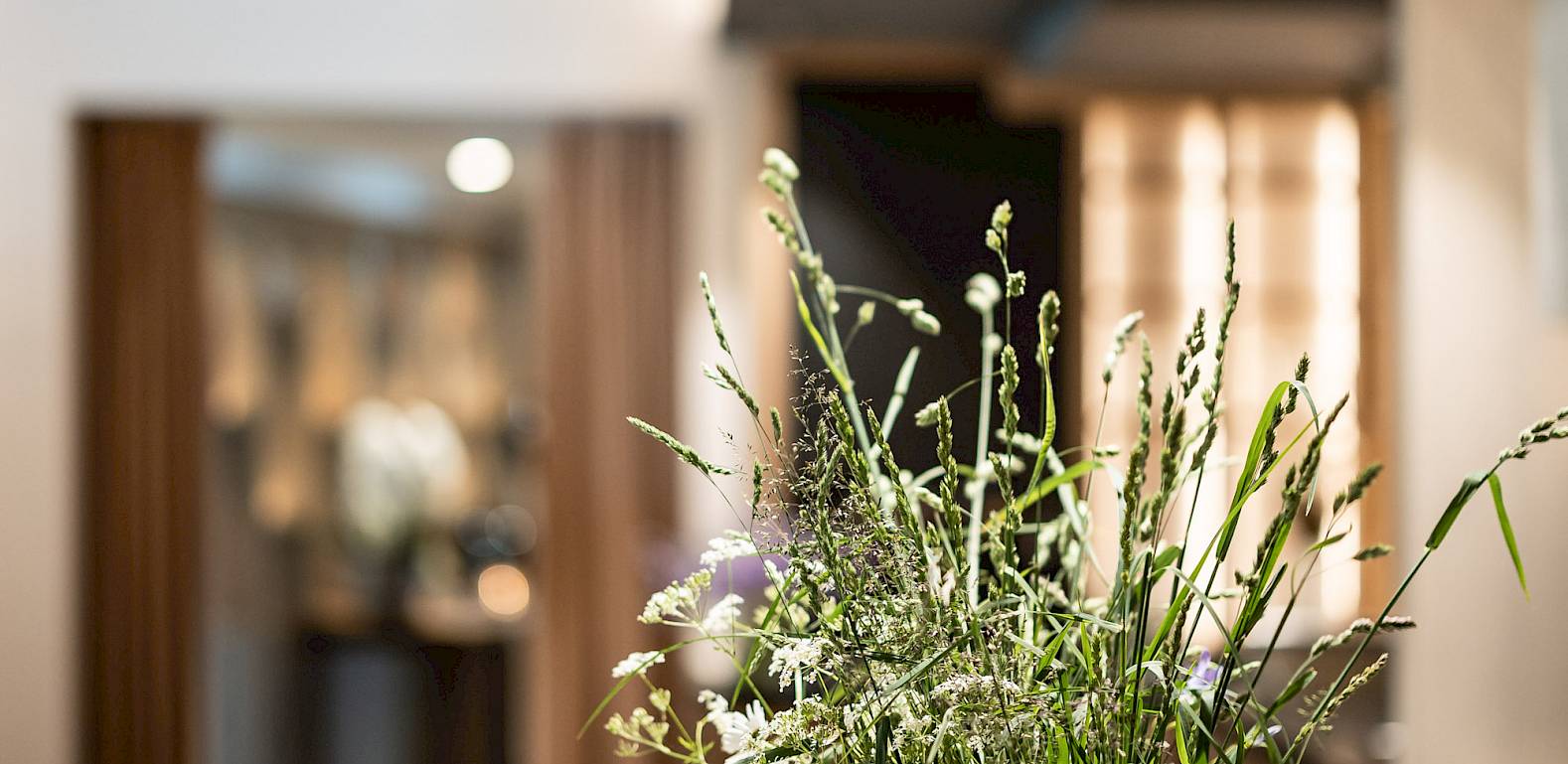 Ein stilvoll dekorierter Tisch mit Wildblumenstrauß und Kerzen in einem modernen, gemütlichen Raum.