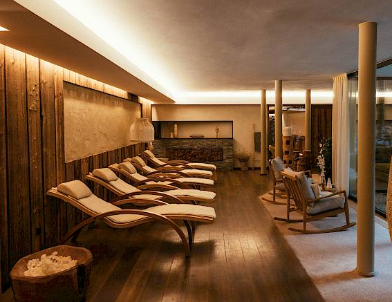Gemütlicher Spa-Ruheraum mit Holzliegen und gedämpftem Licht für Entspannung und Erholung.
