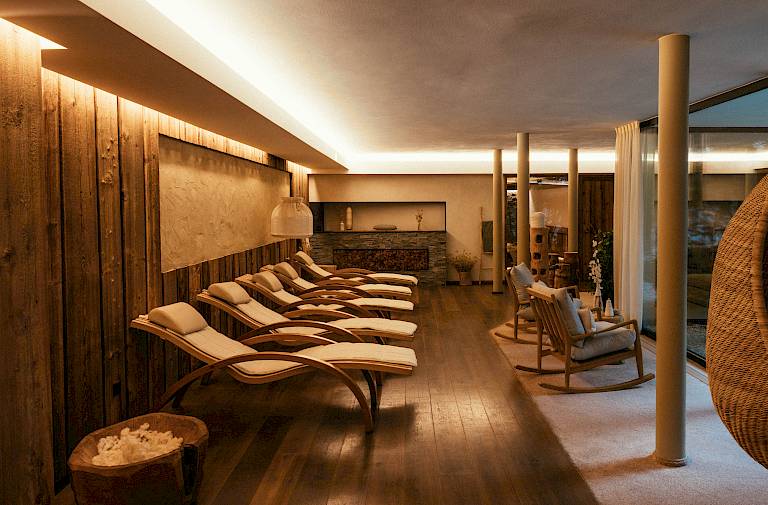 Gemütlicher Spa-Ruheraum mit Holzliegen und gedämpftem Licht für Entspannung und Erholung.