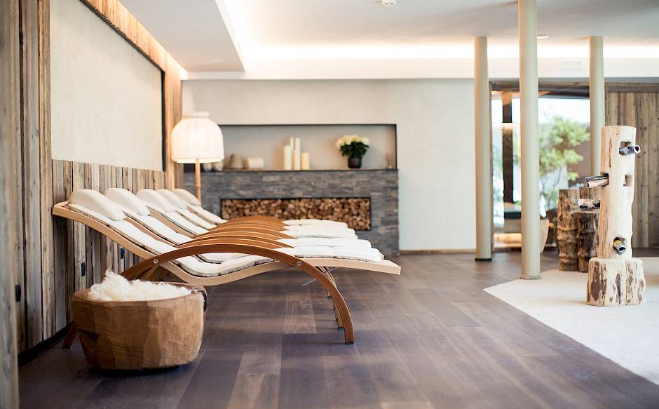 Moderne Wellness-Lounge mit eleganten Holzliegen, Lampe und heller Einrichtung.