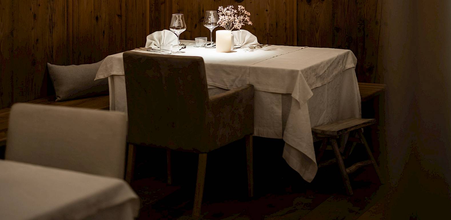 Ristorante accogliente con pareti in legno, illuminazione soffusa e tavolo elegantemente apparecchiato per due.