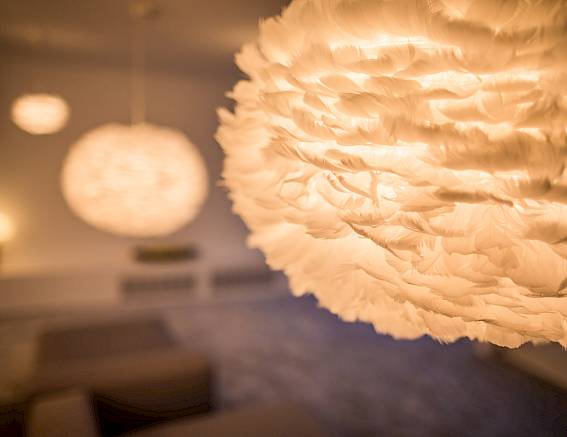 Grandi lampade sospese a forma di piuma illuminano una stanza con un'atmosfera accogliente.