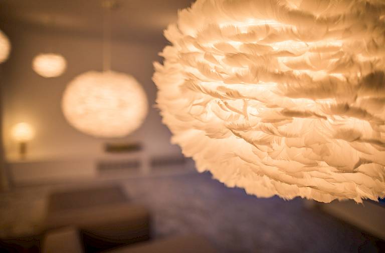 Grandi lampade sospese a forma di piuma illuminano una stanza con un'atmosfera accogliente.