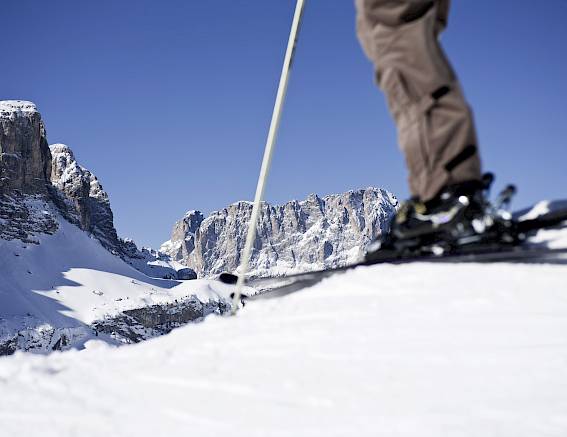 Skifahrer auf schneebedecktem Hang mit majestätischen Bergen im Hintergrund unter blauem Himmel.