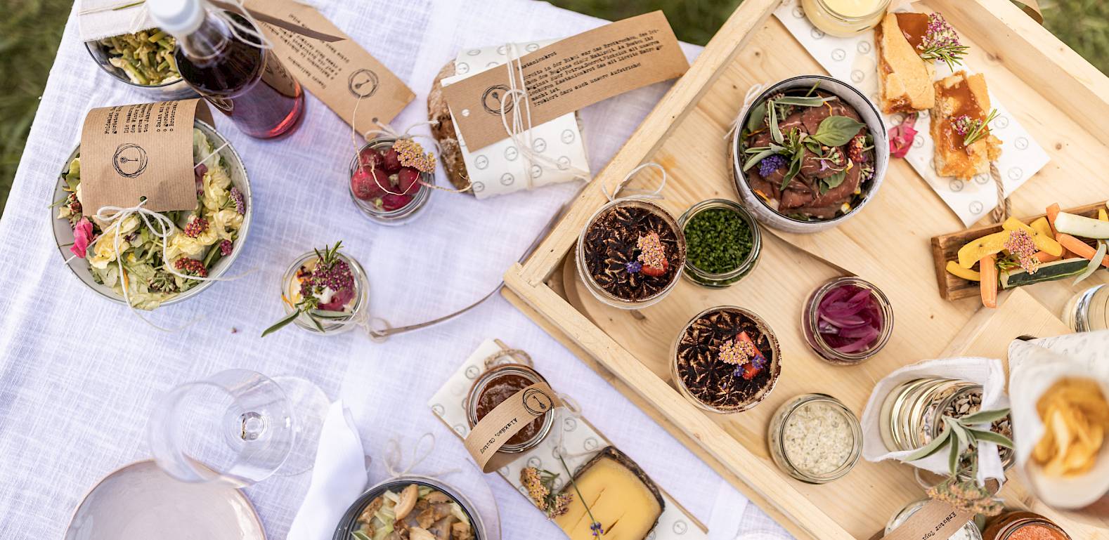 A picnic featuring a variety of small dishes, lovingly arranged on a wooden table outdoors.