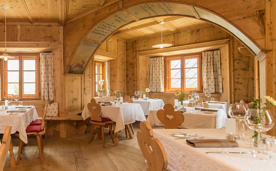 Cozy restaurant with wooden walls, elegant tablecloths, and heart-shaped chairs.