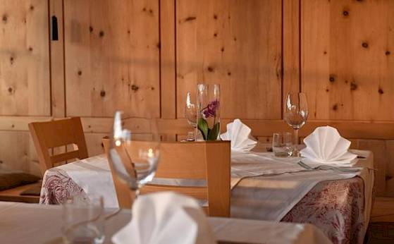 Cozy restaurant with wooden walls, set tables, white napkins, and wine glasses.