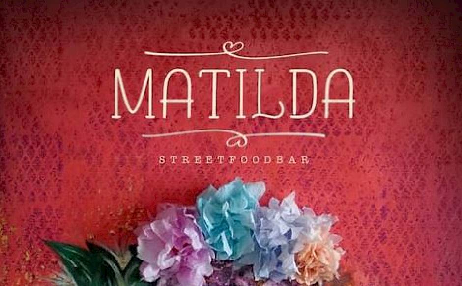 "Matilda Streetfoodbar" in white text on a red background with colorful flowers below.