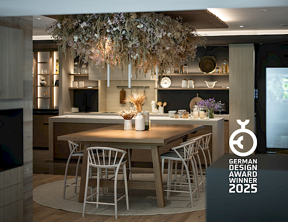Modern kitchen with wood decor, hanging plants, and "German Design Award Winner 2025" accolade.